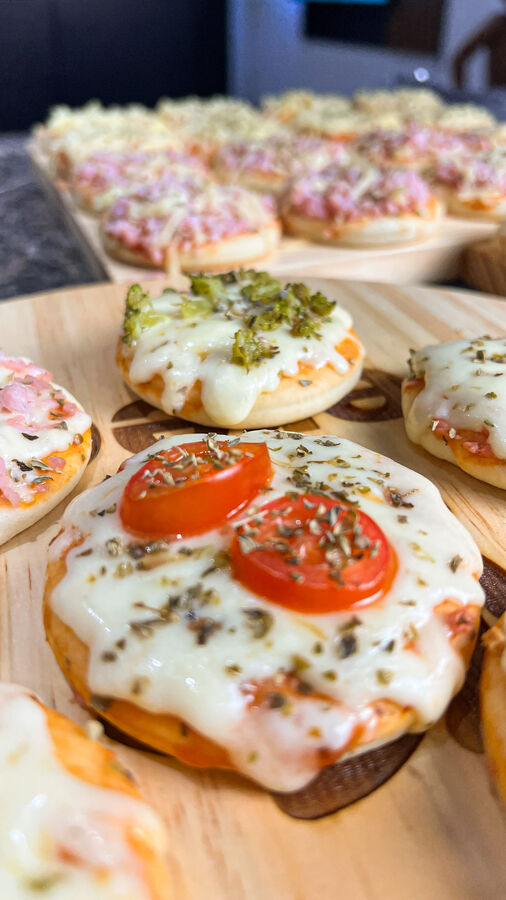 Mini pizzas de tomate, calabresa e brócolis em tábuas de madeira